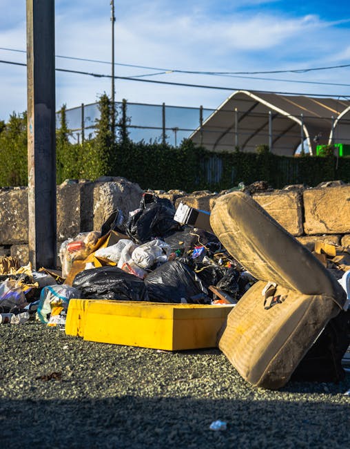 The image shows the rear side of a white commercial van parked on a paved street, with three large blue plastic rubbish bags placed on the ground next to the vehicle. The bags appear to be filled with